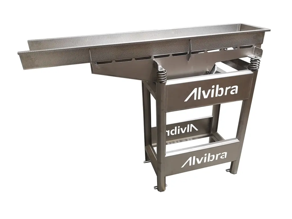 Alvibra-Zuführer. Ein auf der linken Seite offener Korb ist auf einem Vibrationstisch angebracht.