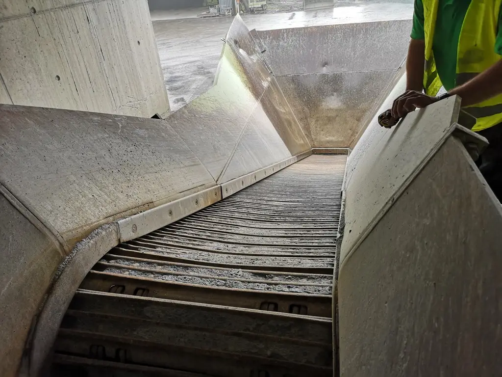 Ein Förderband, das aus seinem Bunker grobes Schüttgut transportiert.