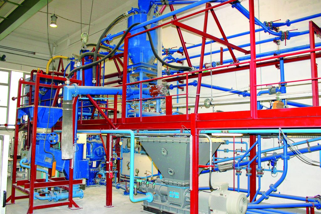 Versuchsanlage der Reel Möller. Unterschiedliche Dosier- und Fördergeräte mit Rohren über eine Metallkonstruktion auf 2 Ebenen.