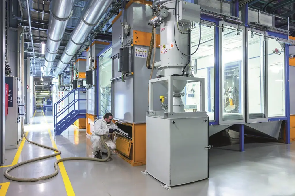 Mitarbeiter saugt in einer Industriehalle einen Filterkasten aus.