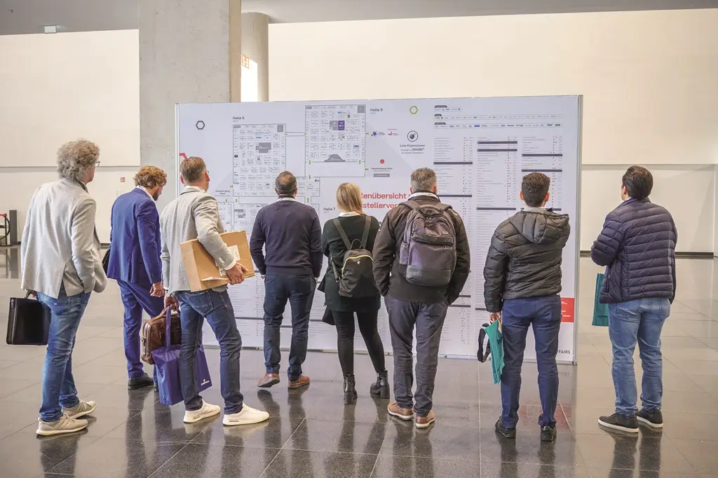 Besucher der Solids 2024 in den Westfalenhallen in Dortmund vor dem Hallenplan