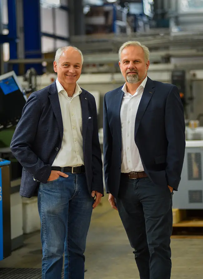 Zwei Geschäftsführer stehen in einer Werkshalle. Links Gerhard Wellmann und rechts Stefan Niehaus.