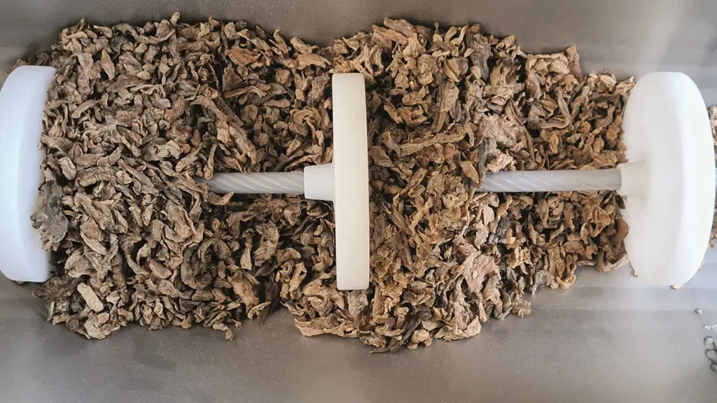 Zwischen Tellerchen eines Seilförderbands liegt getrocknetes Blattwerk oder Gewürz.