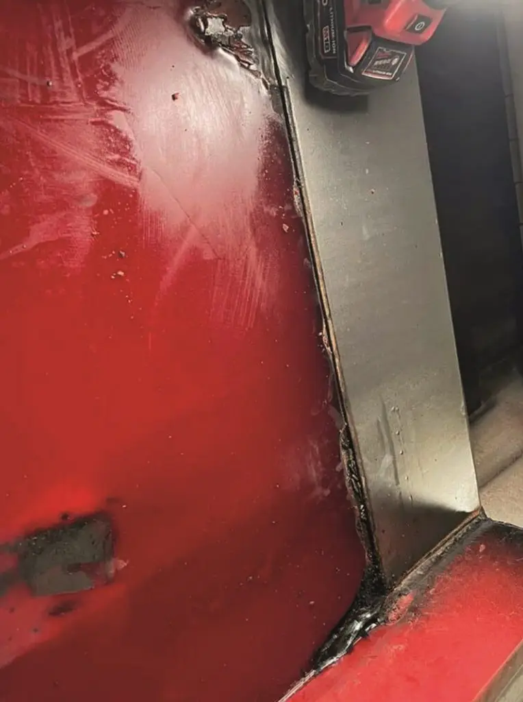 Industriemaschine, die mit einem spachtelbaren Verschleißschutz repariert wurde. Im Vordergrund eine rot lakierte Maschine und eine Aluminiumplatte auf der eine Handschleifmaschine steht.