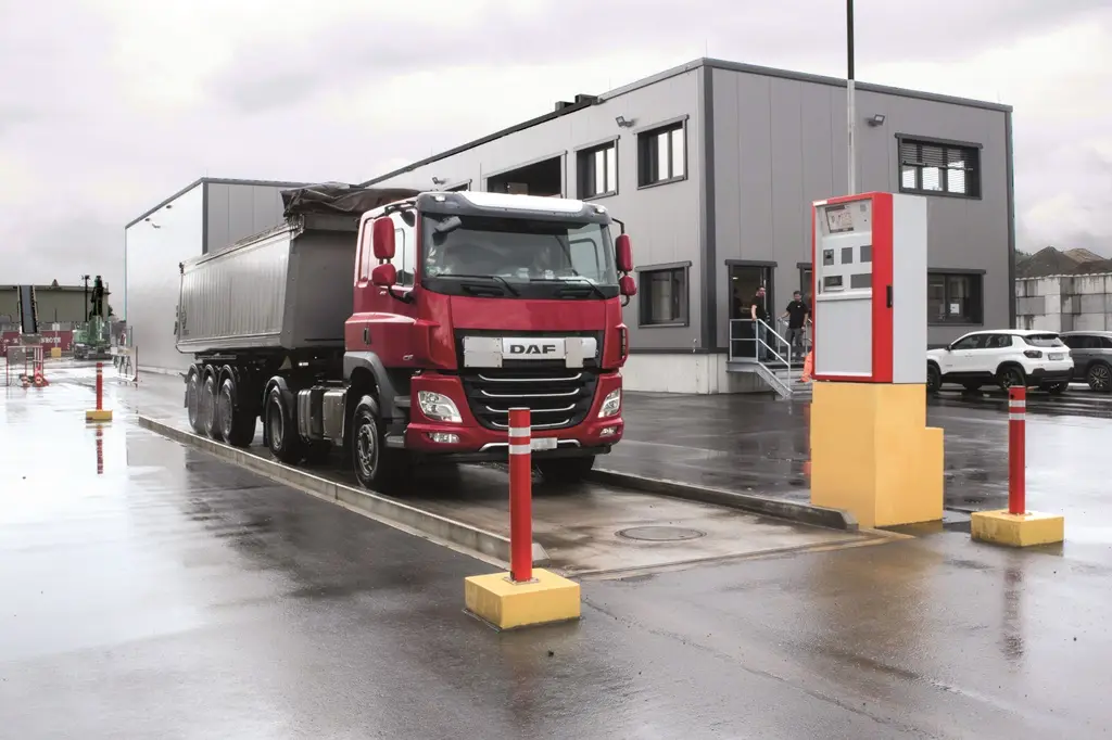 Lastwagen fährt auf eine Waage. Das Wägeterminal ist in Höhe des Fahrers.