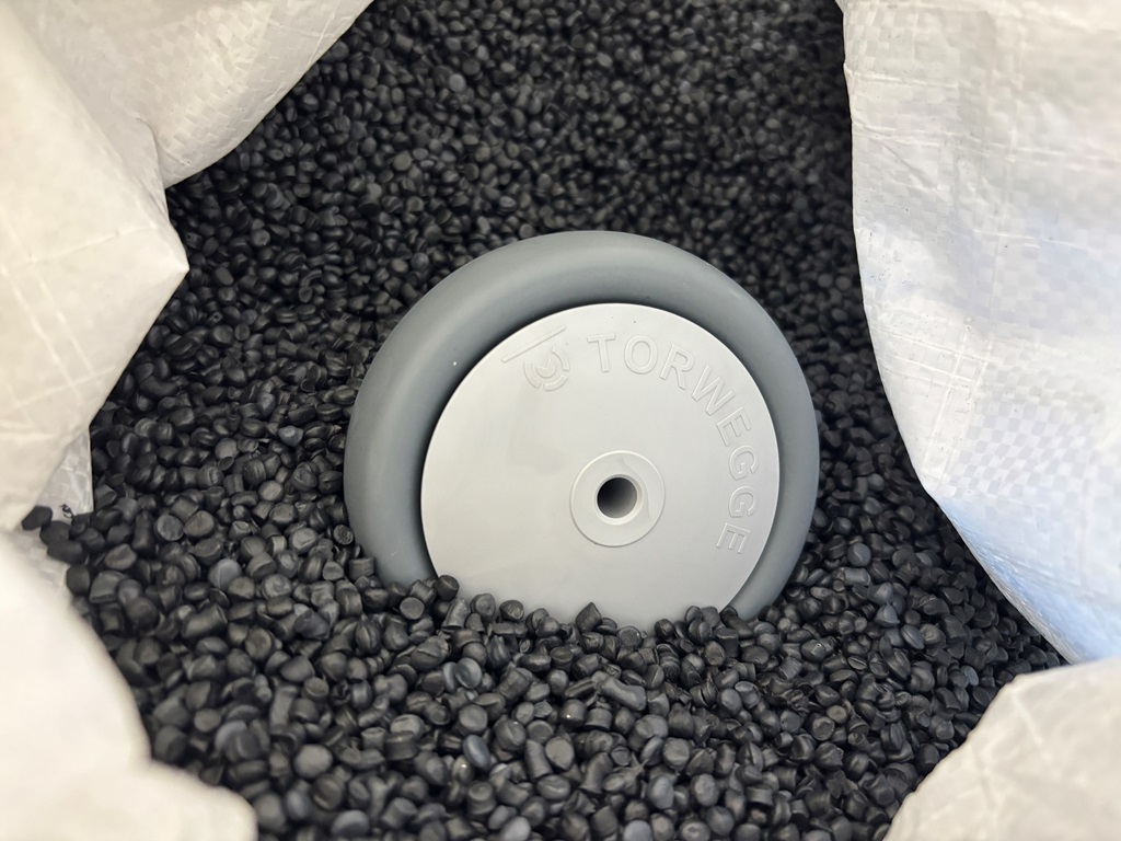 Kunststoffrad liegt in einem Big Bag, mit dunklem Granulat gefüllt.