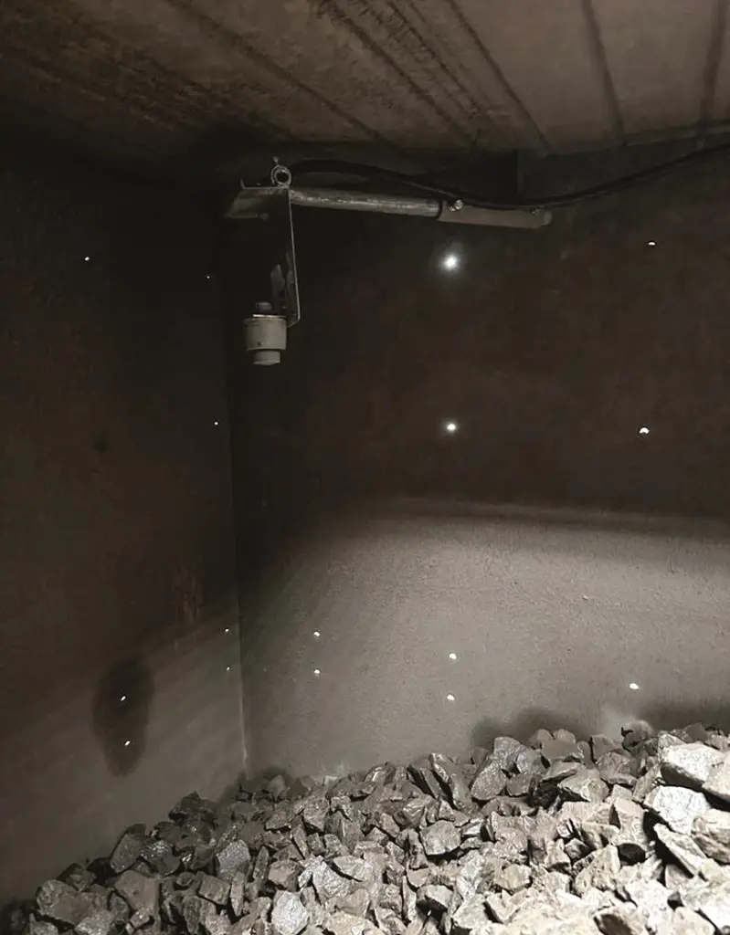 Bunker mit Gestein und einem darüber angebrachten Sensor. Alles grau in grau.