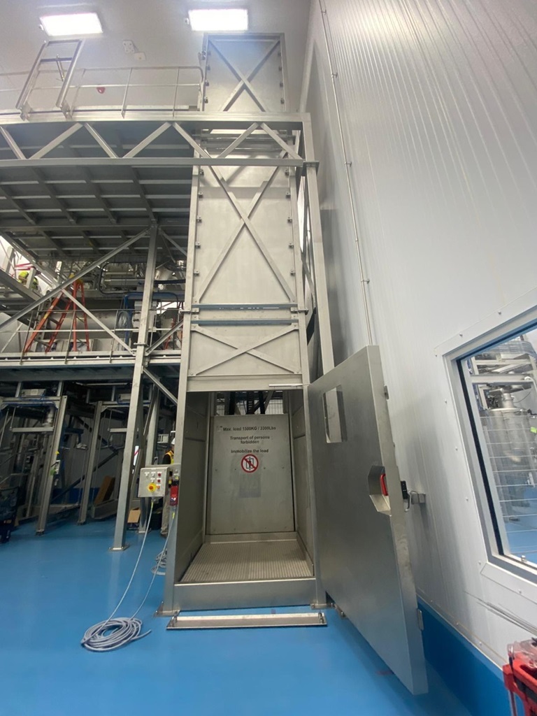 Warenaufzug in einer Industriehalle, der vom EG in höhere Etagen der Stahlkonstruktion gebaut ist.