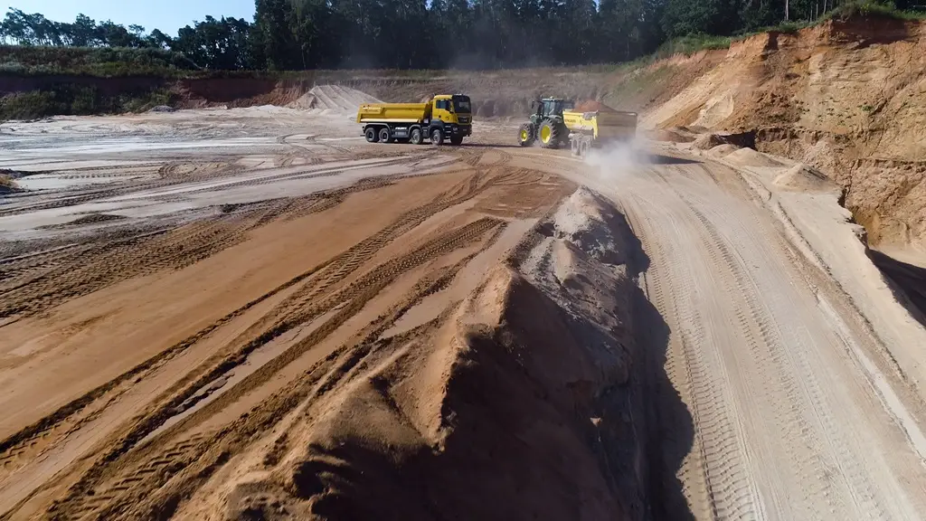 Ein Lastwagen und ein Bagger mit Anhänger in einer Sandabbaugrube