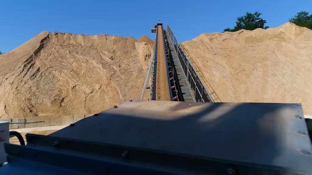 Blick auf eine Sandhalde, die durch ein Förderband getrennt ist