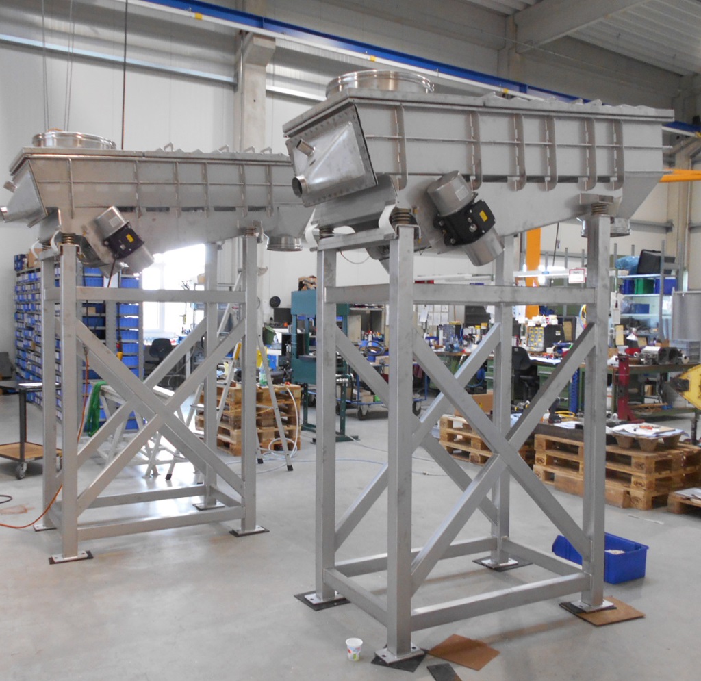 Zwei Vibrationsrinnen der NetterVibration auf hohem Gestellen in der Produktionshalle des Herstellers