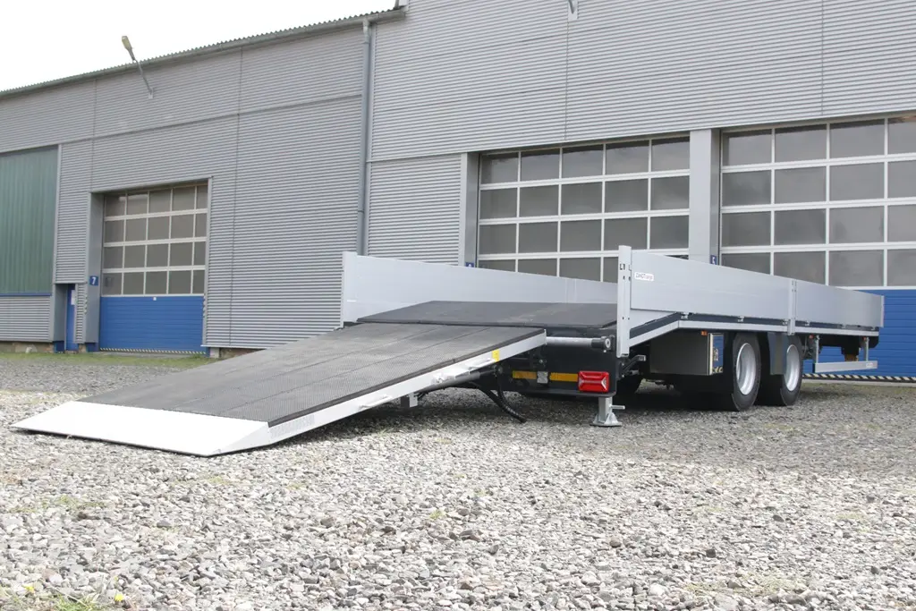 Lastwagenanhänger mit heruntergeklappter Rampe vor einem Industrie-Roll-Tor