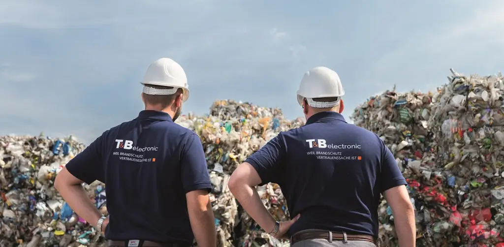 Mitarbeiter der T&B elektronic mit dem Rücken zu uns vor Material auf einem Recyclinghof.
