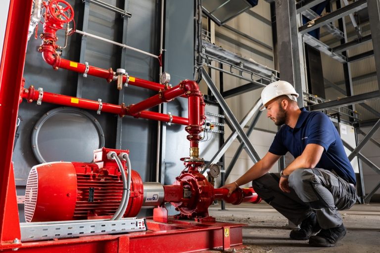 Ein Mann kniet neben einer industriellen Pumpe für die Löschwasserversorgung.