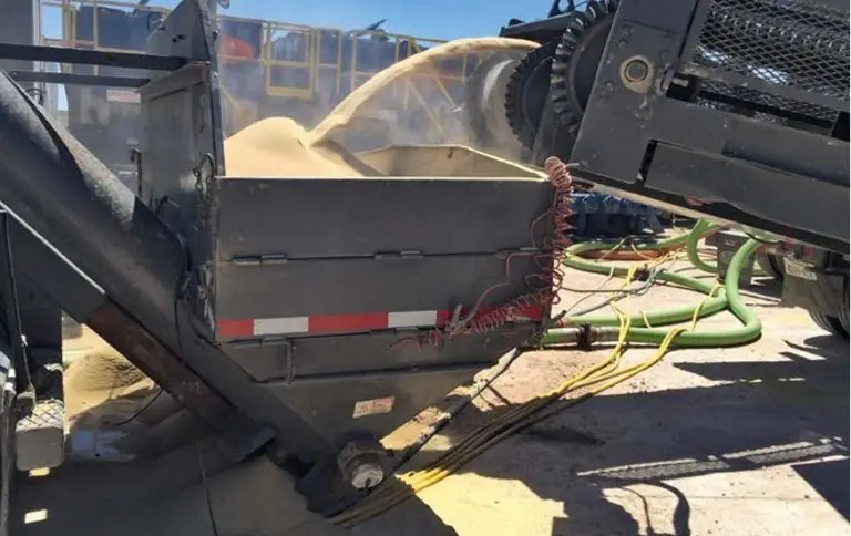Auf einem Außengelände füllt ein Förderband Fracking-Sand in einen Mischer-Einfülltrichter.