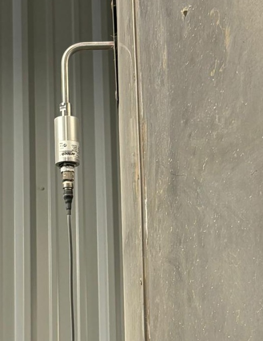 Ultraschallkonverter am Sprühtrockner außen am Konverter vor einer Metallhallenwand.