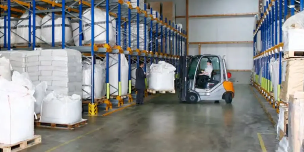 Lagerhalle mit blauen regalen undd einem grauen gabelstapler