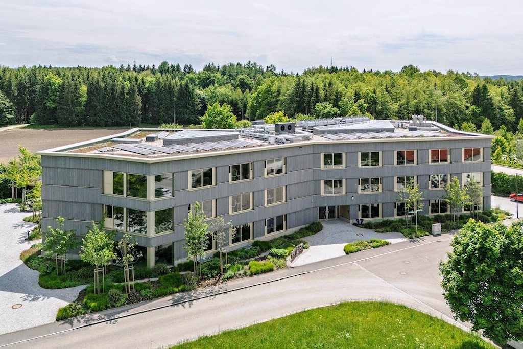 Gebäude mit Parkplatz und anliegendem Wald