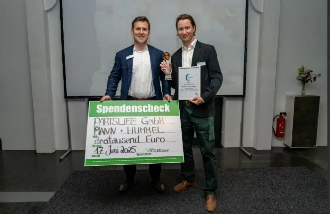 Zwei Männer in Anzug halten einen grünen Spendencheck