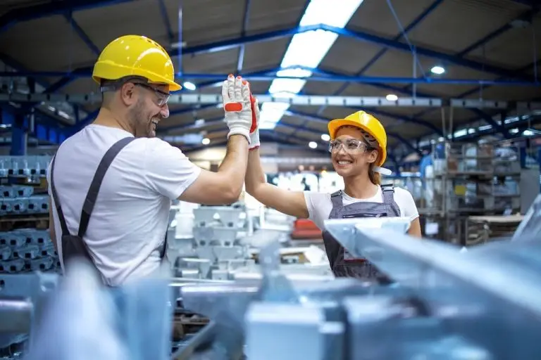 Zwei Menschen in einer Industriehalle geben sich ein Highfive.