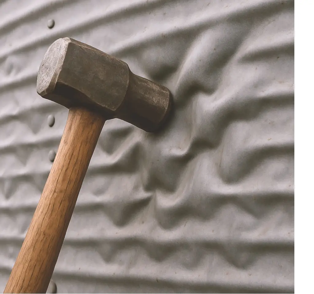 Ein Hammer deformierte eine leicht gewellte Metallplatte