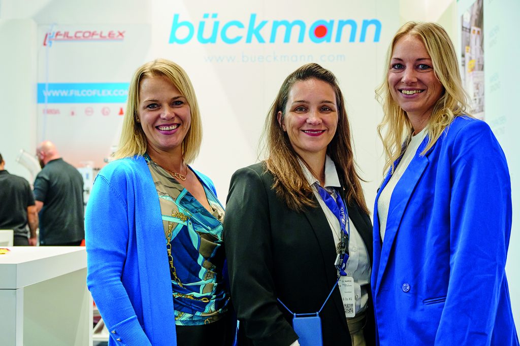 Julia Heinzel, Sonja Goertz, Sarah Neumann alle Mitarbeiterinnen der bückmann Lohnaufbereitung stehen am Messestand der Powtech Technopharm 2025