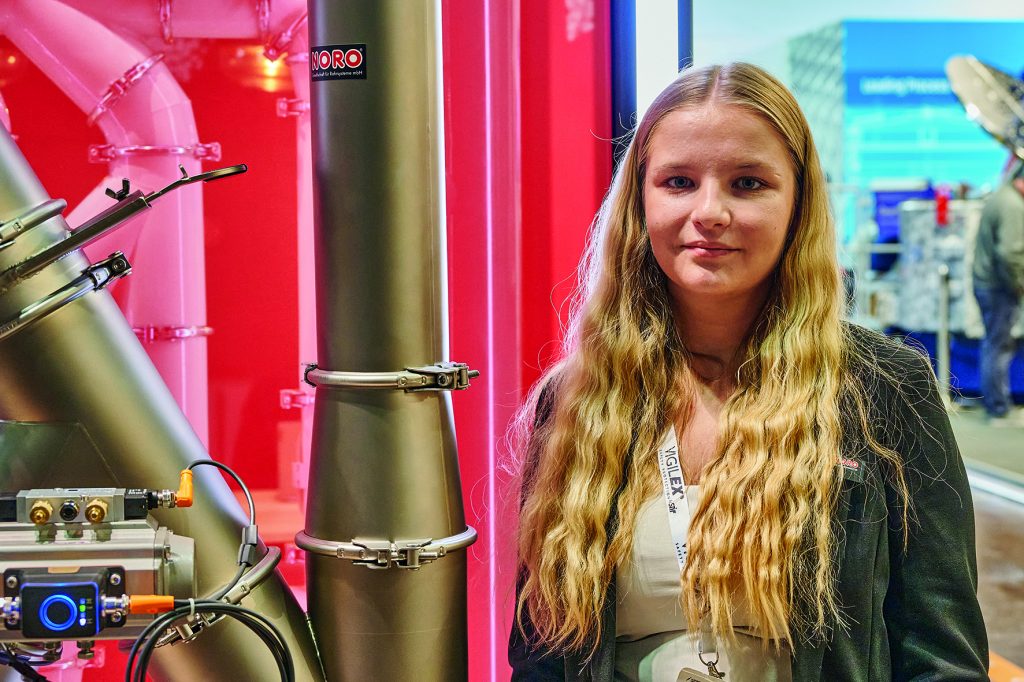 Lara Tiedemann, Mitarbeiterin der NORO Rohrsysteme steht am Messestand der Powtech Technopharm 2025