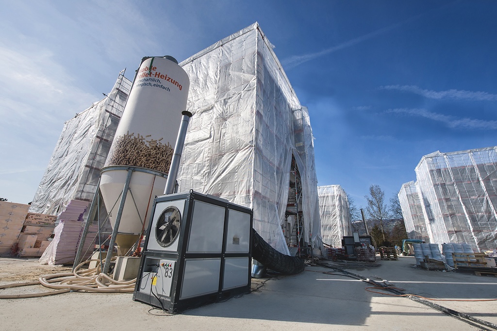 Baustelle mit Baugerüsten. Im Vordergrund eine Baustellenheizung.