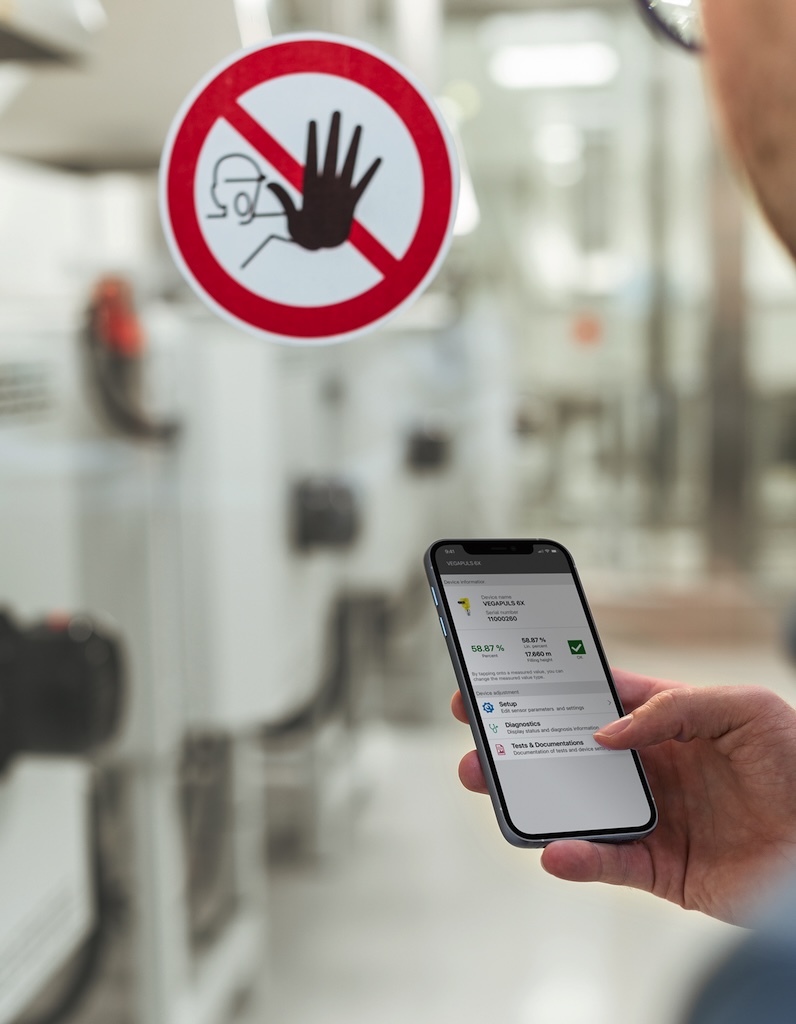 Smartphone im Vordergrund im Hintergrund eine Verbotsschild und Industrieanlagen