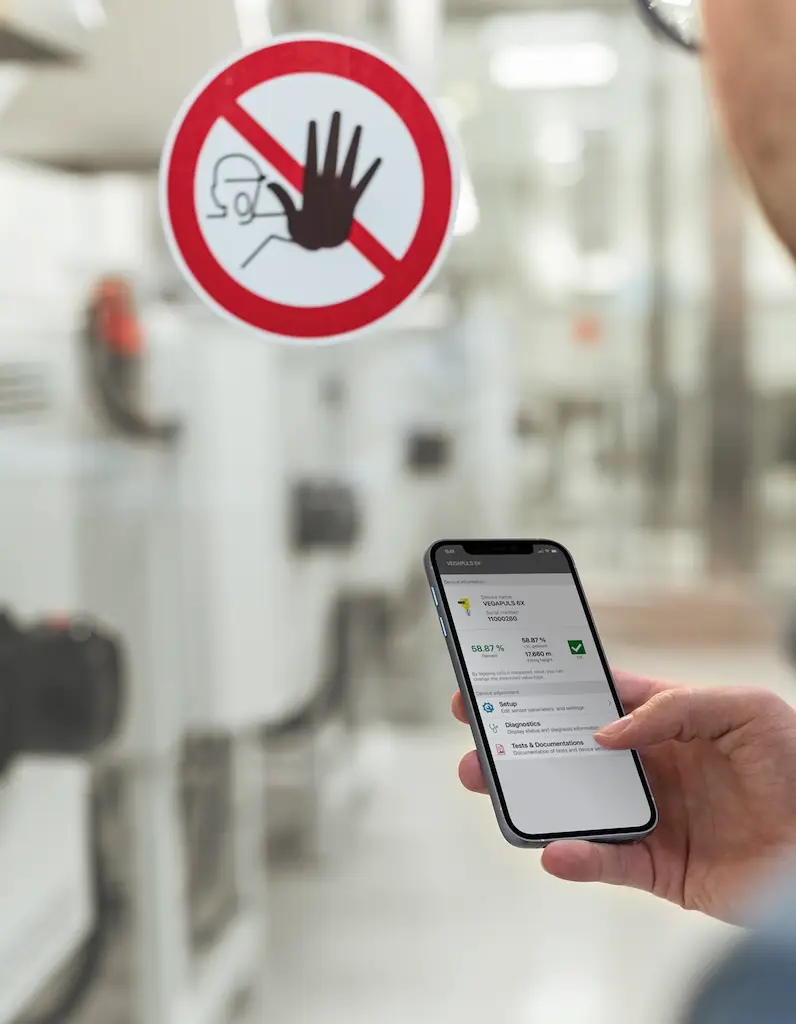 Smartphone im Vordergrund im Hintergrund eine Verbotsschild und Industrieanlagen