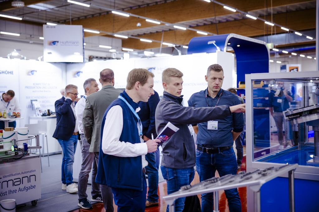 Menscehn auf einer Fachmesse, die sich über Fachthemen diskutieren.