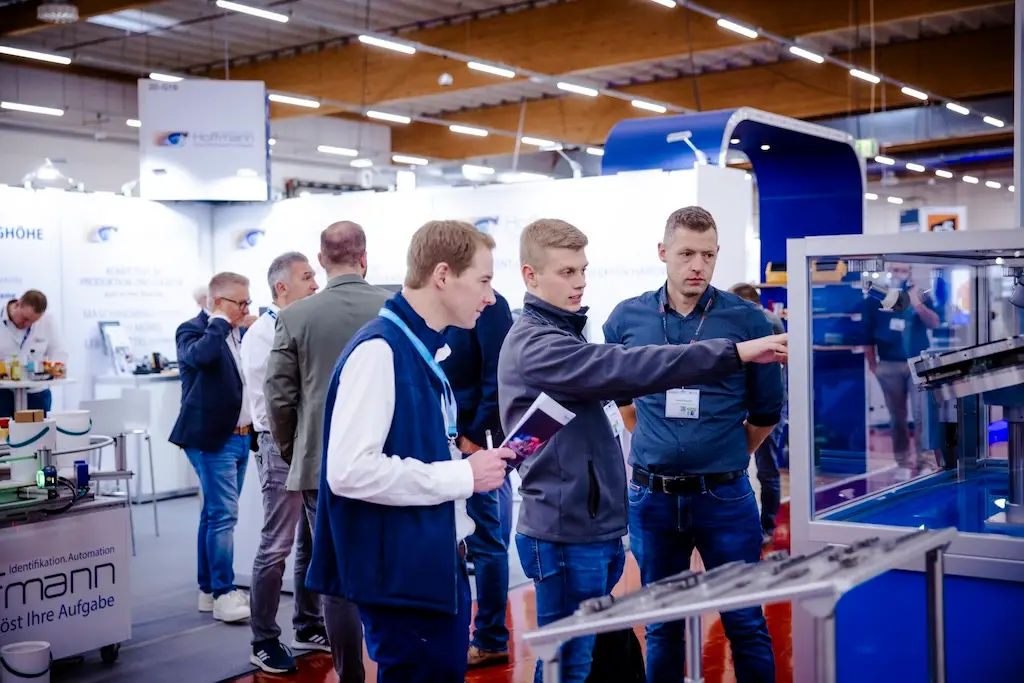 Menscehn auf einer Fachmesse, die sich über Fachthemen diskutieren.