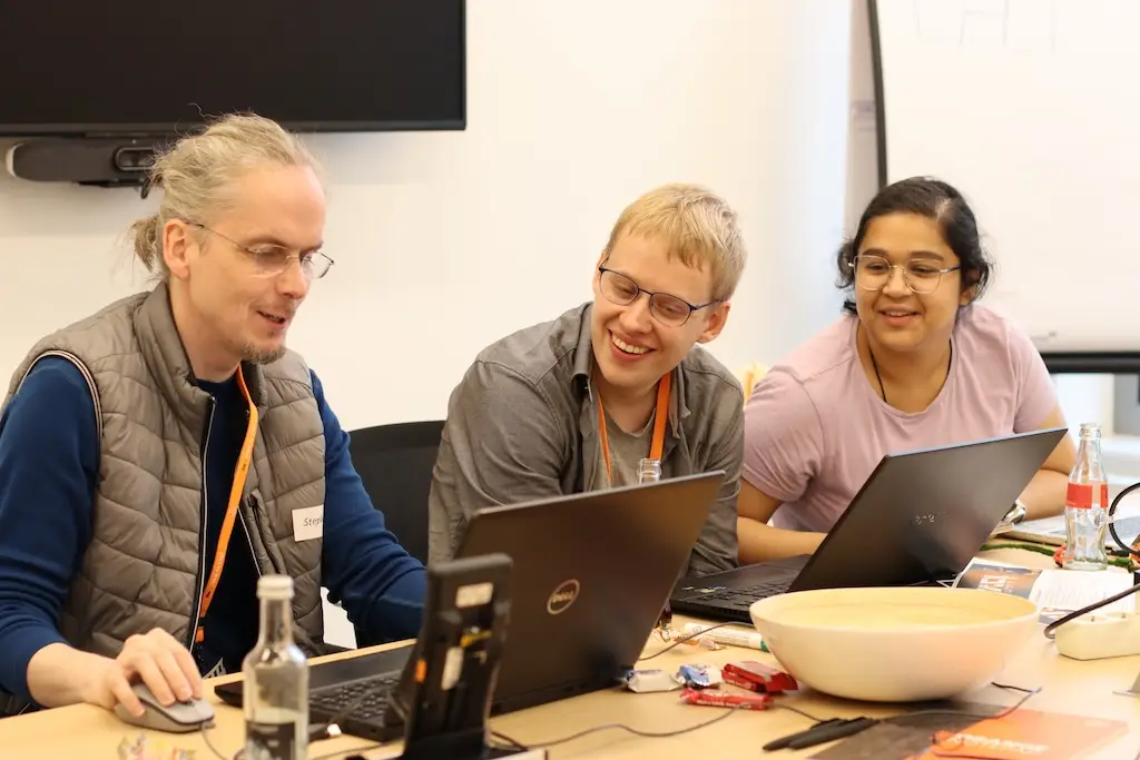 Drei Menschen vor Laptops