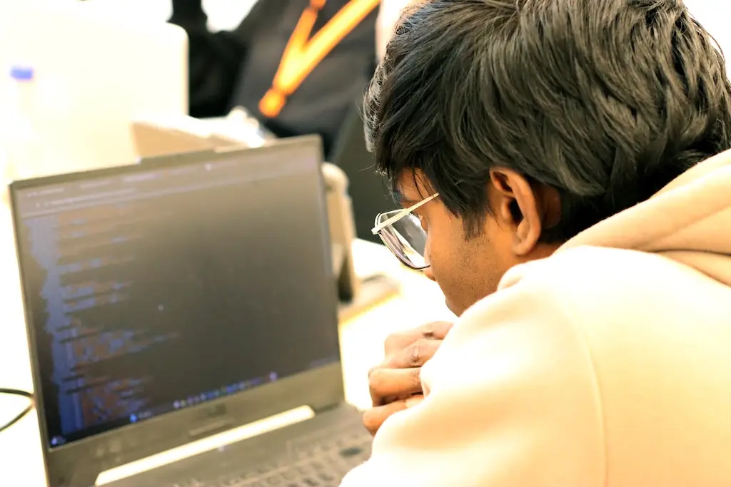 Ein junger Mann sitzt vor einem Laptopbildschirm