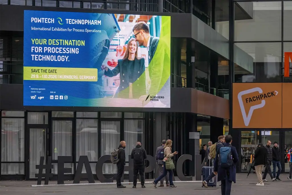 Gebäude mit großen Powtech Technopharm Bildschirm. Im Vordergrund Passanten