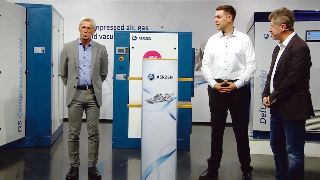 3 Herren stehen mit Micros auf einem Messestand