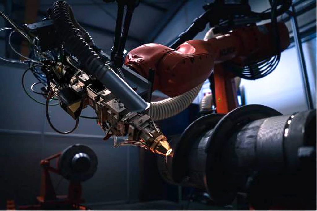 Eine Industrieschnecke wird über einen Laserbeschichtungsprozess beschichtet. Vorne ein Lasergerät hinten die Schnecke