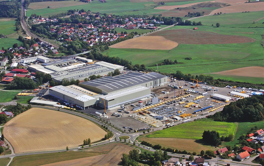 Großer Firmenkomplex umgbeen von Parkplätzen einem dorf und Feldern