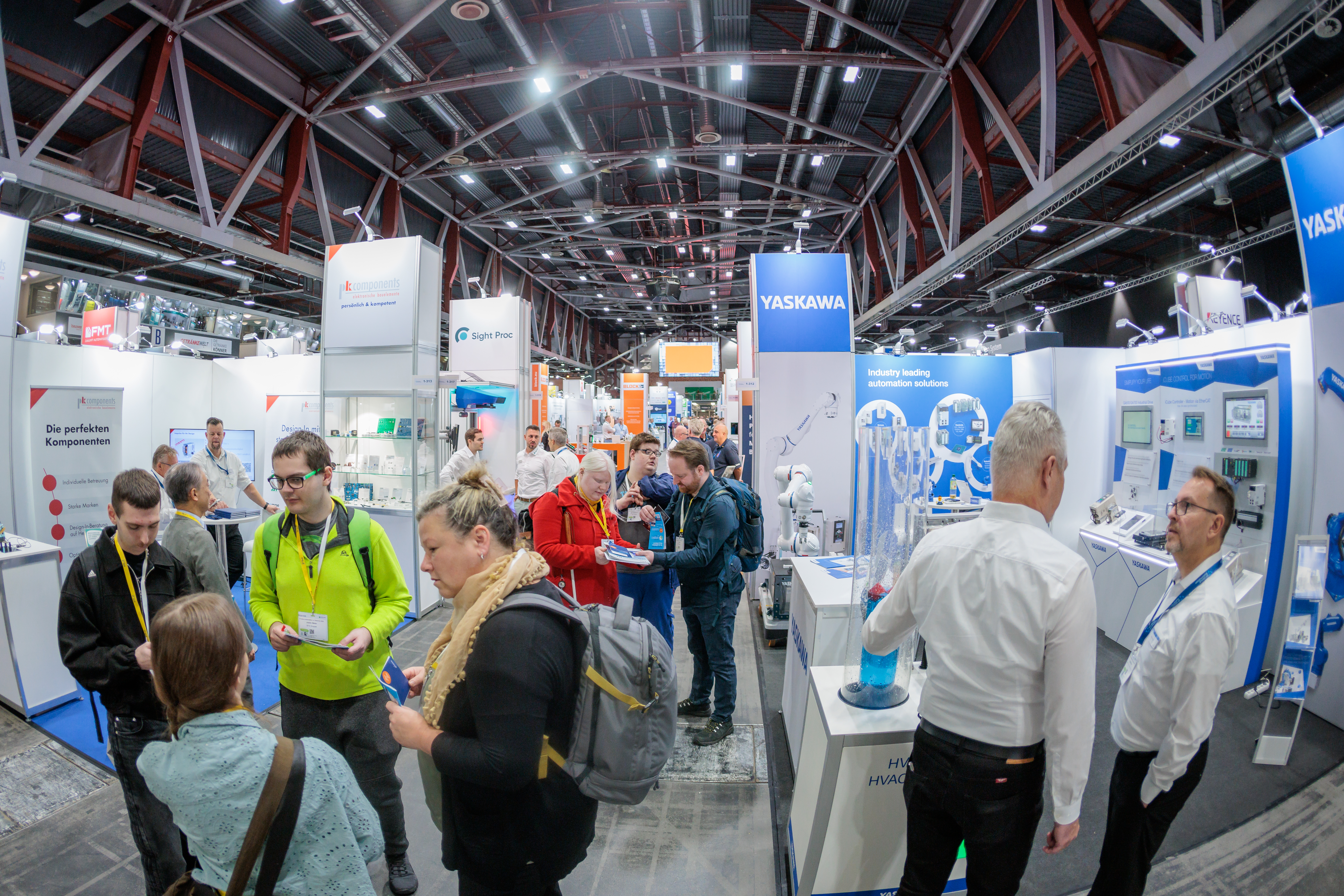 Messebetrieb. Viele Menschen dei zwishcen messestädne in einer Messehalle stehen