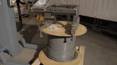 Ein Mitarbeiter bewegt mit einer Hebehilfe eine Kabeltrommel