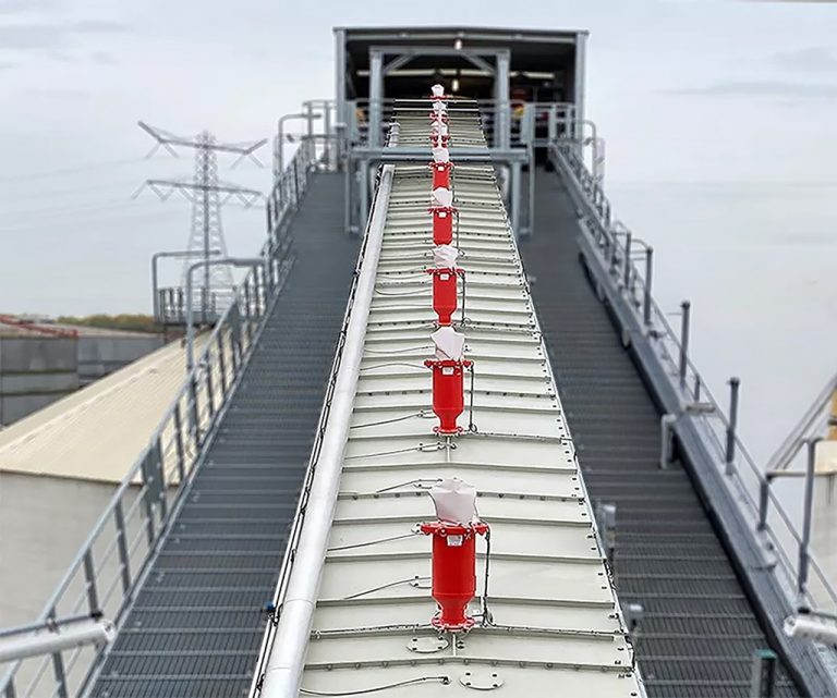 Reihe von Stuvex Flash Explosionsunterdrückungsmodulen auf der Abdeckung eines Förderbands in einer industriellen Schüttgut- oder Zuckerfabrik; Schutz gegen Staubexplosionen entlang der Förderstrecke.