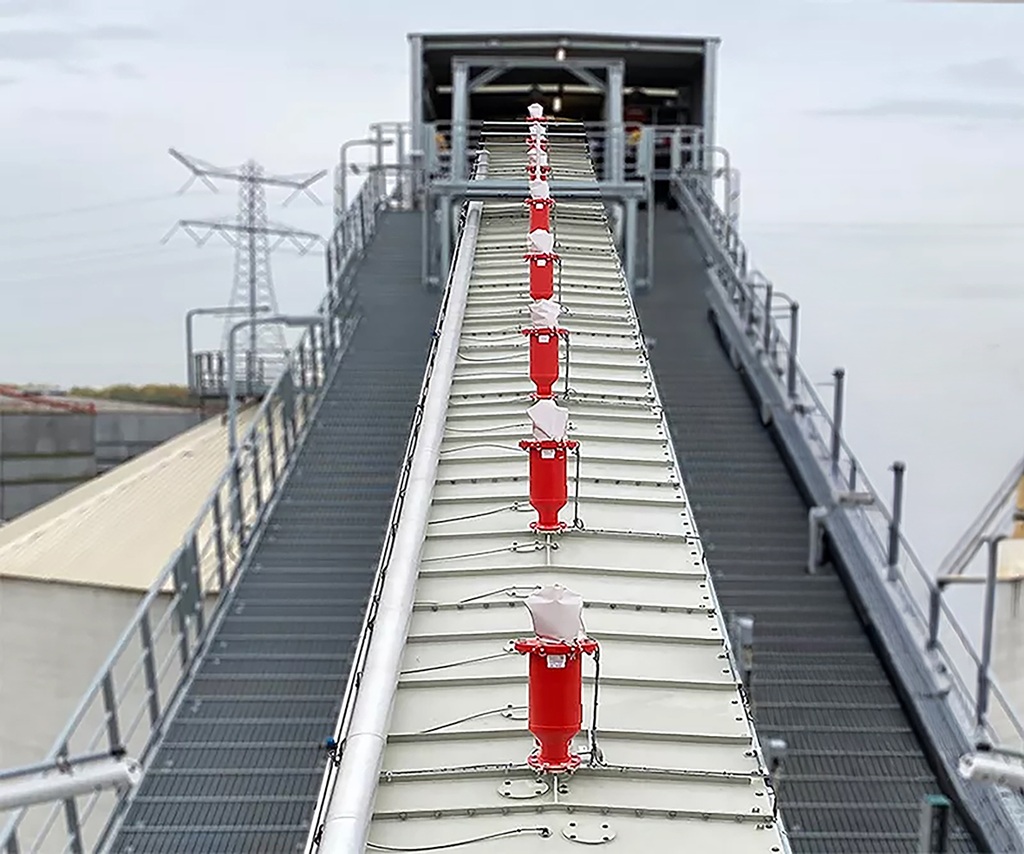 Reihe von Stuvex Flash Explosionsunterdrückungsmodulen auf der Abdeckung eines Förderbands in einer industriellen Schüttgut- oder Zuckerfabrik; Schutz gegen Staubexplosionen entlang der Förderstrecke.