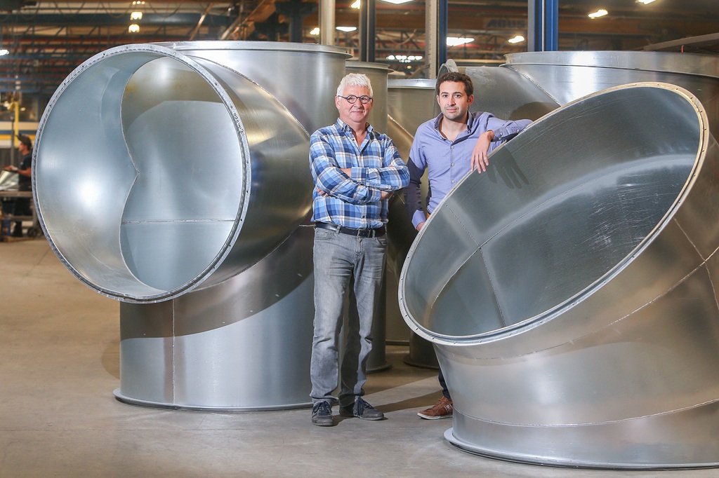 (v. l. n. r.) Jan und Tim Stinkens stehen vor großen Rohrelementen in einer Industriehalle