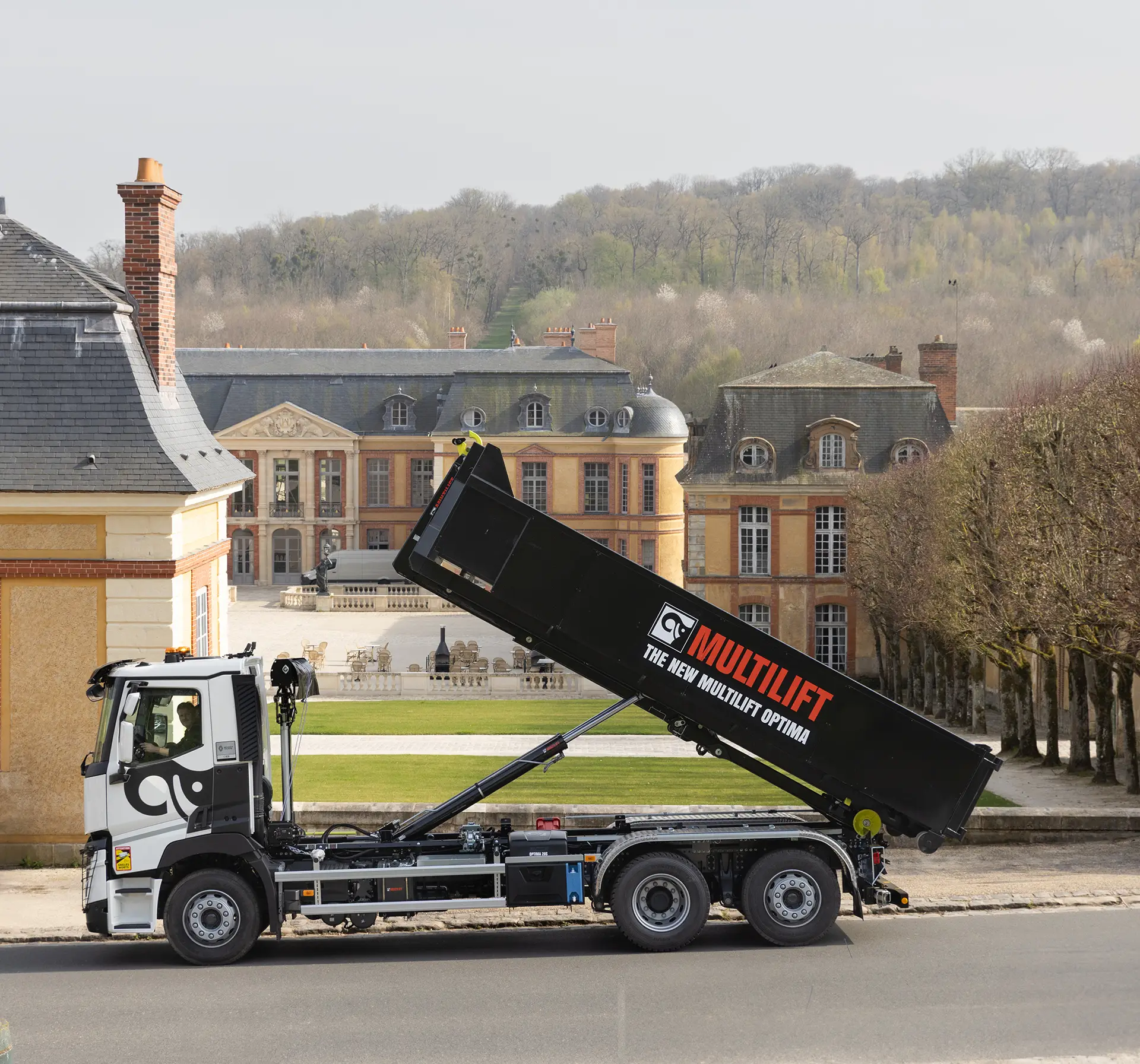 Vor einem Renaissanceschlösschen steht ein Kipper-Lastwagen mit hochgestellter Ladefläche.