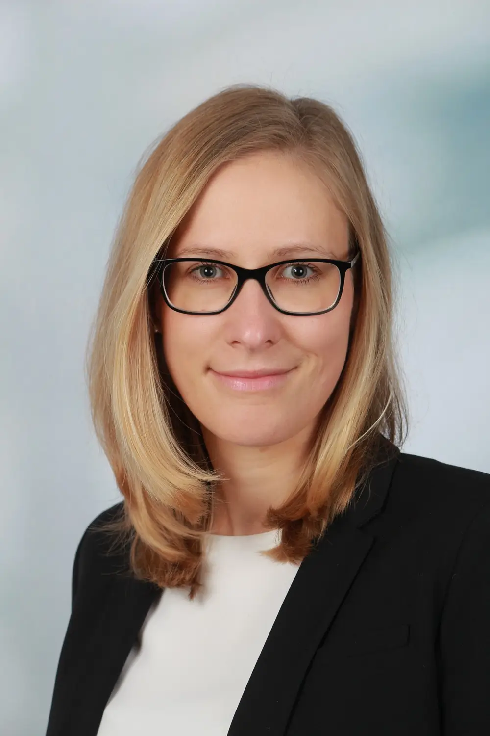Porträtaufnahme einer Person mit Brille vor hellem Hintergrund.