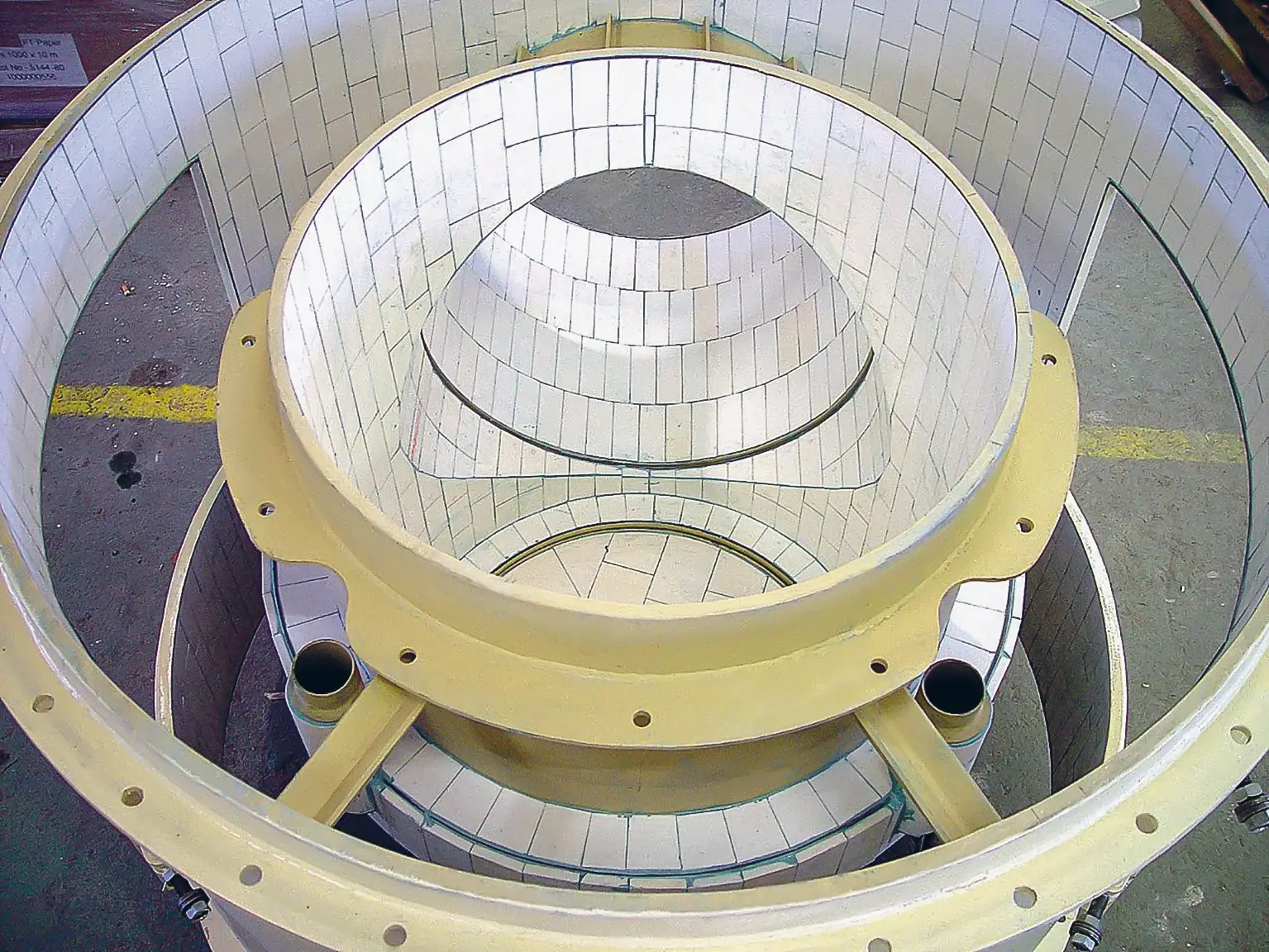 Draufsicht auf einen vollständig mit KALOCER-Keramikplatten ausgekleideten Sichterkopf in gelbem Stahlgehäuse; die konzentrischen Auskleidungsringe zeigen die präzise Verlegung der Verschleißschutzelemente