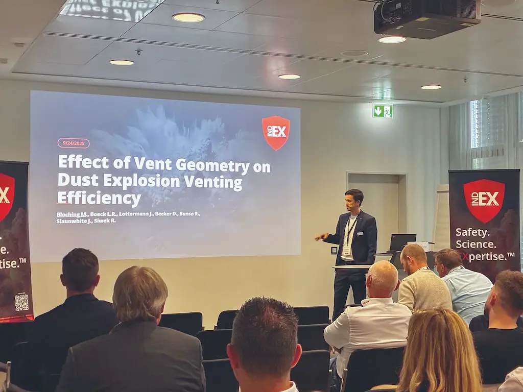 Referent präsentiert auf der IndEX-Konferenz einen Fachvortrag zum Thema „Effect of Vent Geometry on Dust Explosion Venting Efficiency" vor einem Fachpublikum im Konferenzsaal
